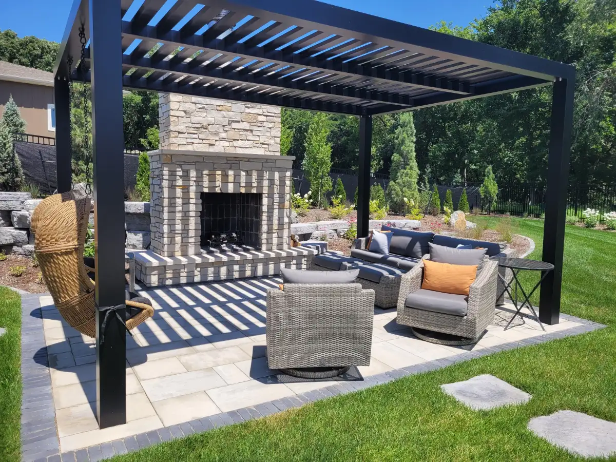 Black pergola with stone fireplace, wicker furniture, and stepping stones