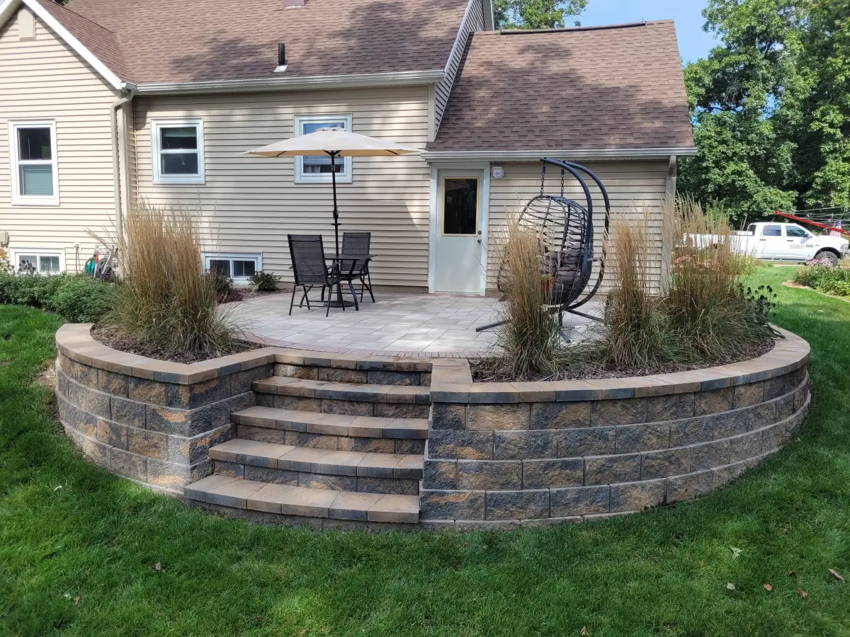 Elevated patio with bistro table, hanging chair, and ornamental grasses