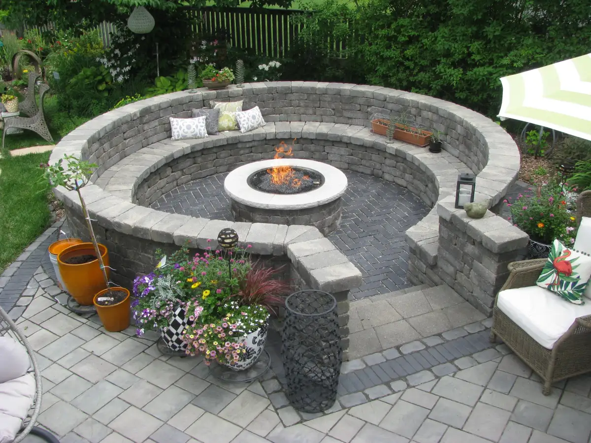 Gas fire pit lit at dusk with curved seating wall and colorful flowers
