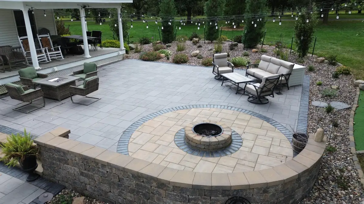 Two-tone circular fire pit with string lights and putting green
