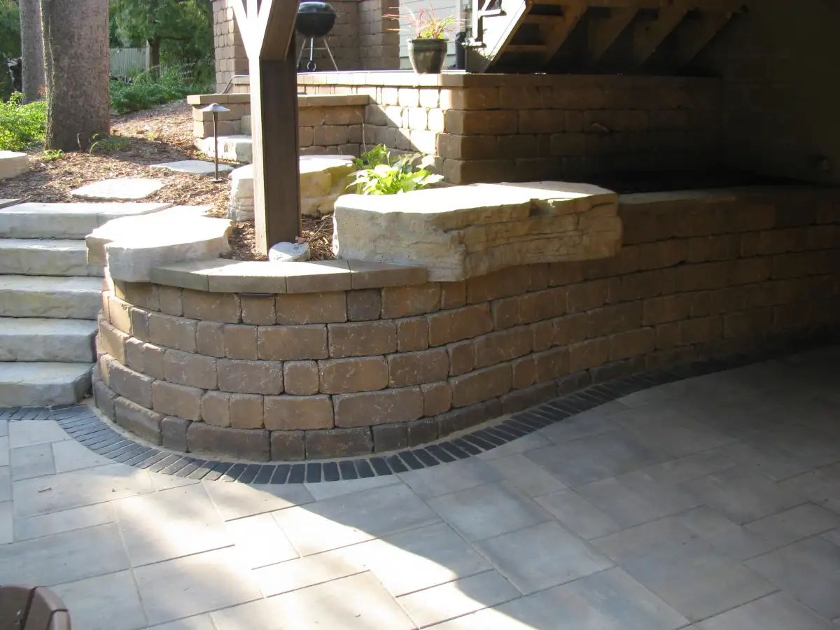 Curved stone retaining wall with steps under deck