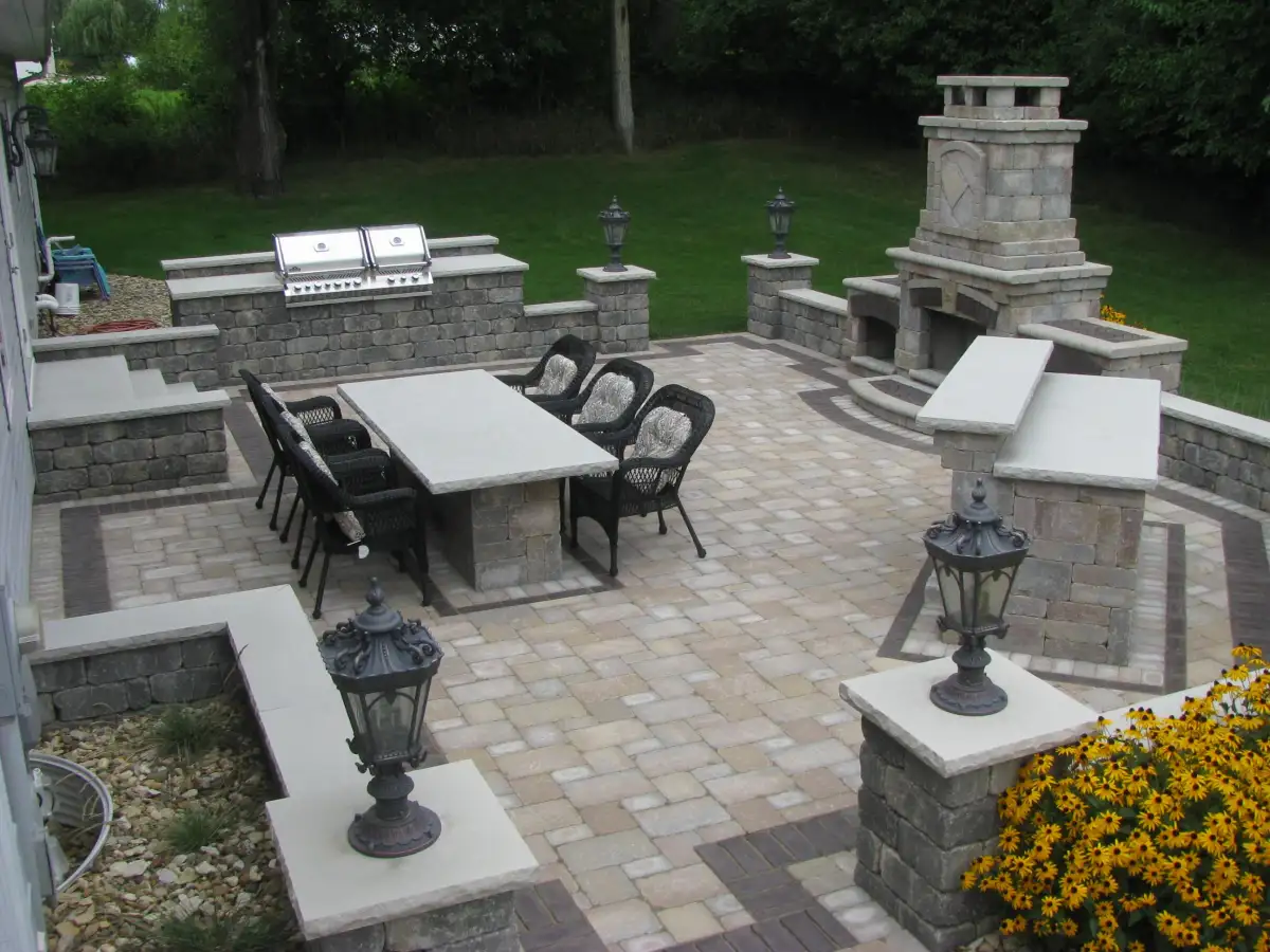 Stone outdoor fireplace with built-in grill station and paver patio