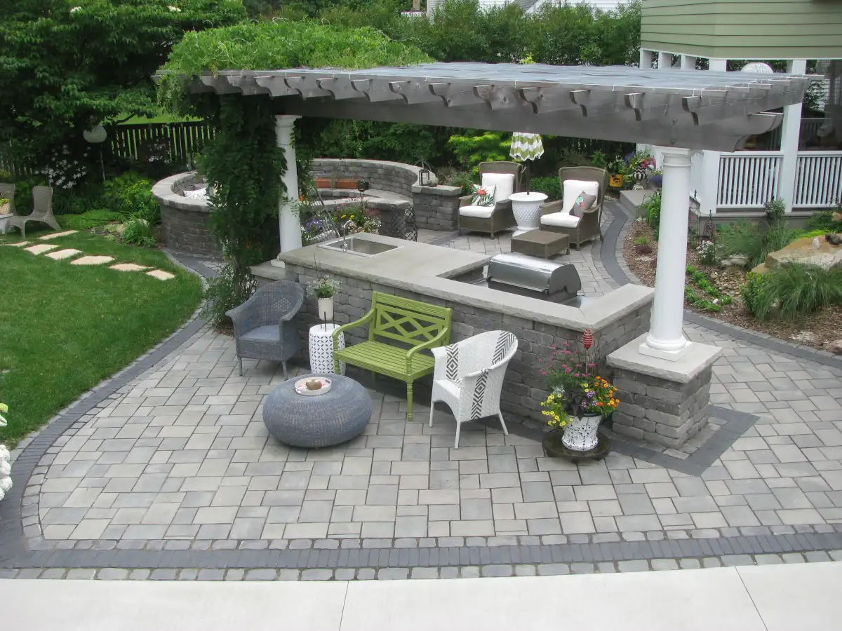 Outdoor kitchen with pergola, stone island, and built-in grill