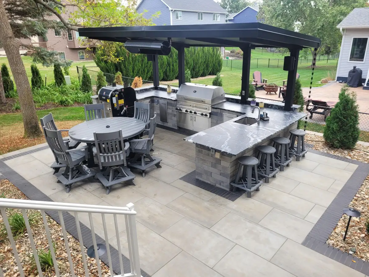 Outdoor kitchen with black metal pavilion, granite countertops, and built-in grill