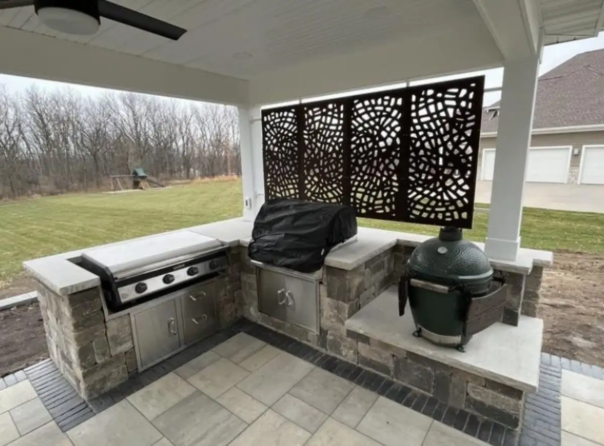 Covered kitchen with decorative privacy screens, grill, and smoker