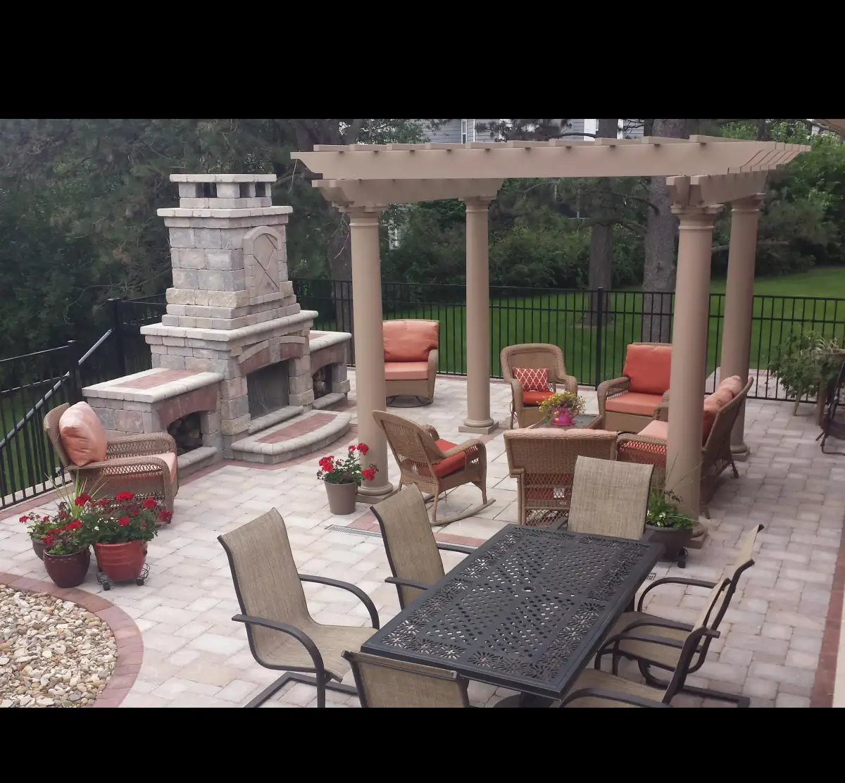 Outdoor fireplace with pergola, wicker furniture, and dining set
